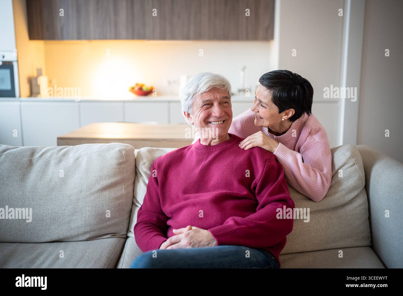 Heureux couple âgé assis ensemble sur le canapé riant et parlant à la maison. L'amour familial des personnes âgées Banque D'Images