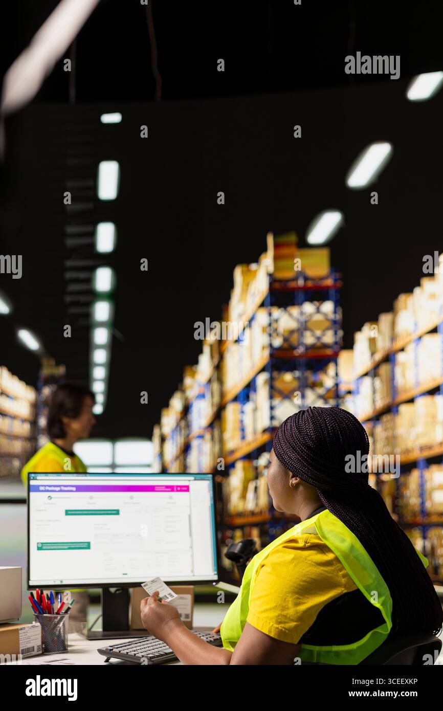 Afro-américaine plaçant des étiquettes d'expédition adhésives sur des boîtes en carton, préparant les colis pour la livraison express et appliquant awb pour le suivi de l'état des colis sur un logiciel pc. Banque D'Images