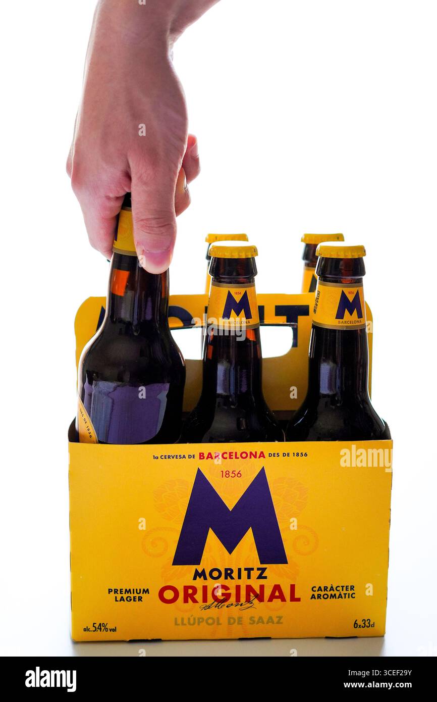 Barcelone, Espagne - 7 Augusto 2025, jeune homme prenant une bouteille de bière dans un étui en carton de six paquets sur fond blanc Banque D'Images