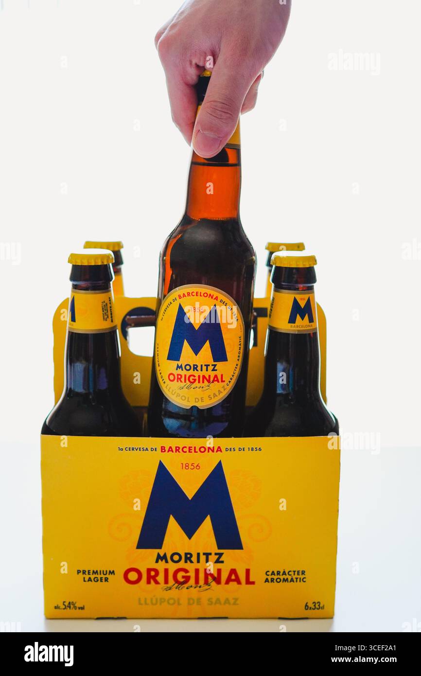 Barcelone, Espagne - 7 Augusto 2025, jeune homme prenant une bouteille de bière dans un étui en carton de six paquets sur fond blanc Banque D'Images