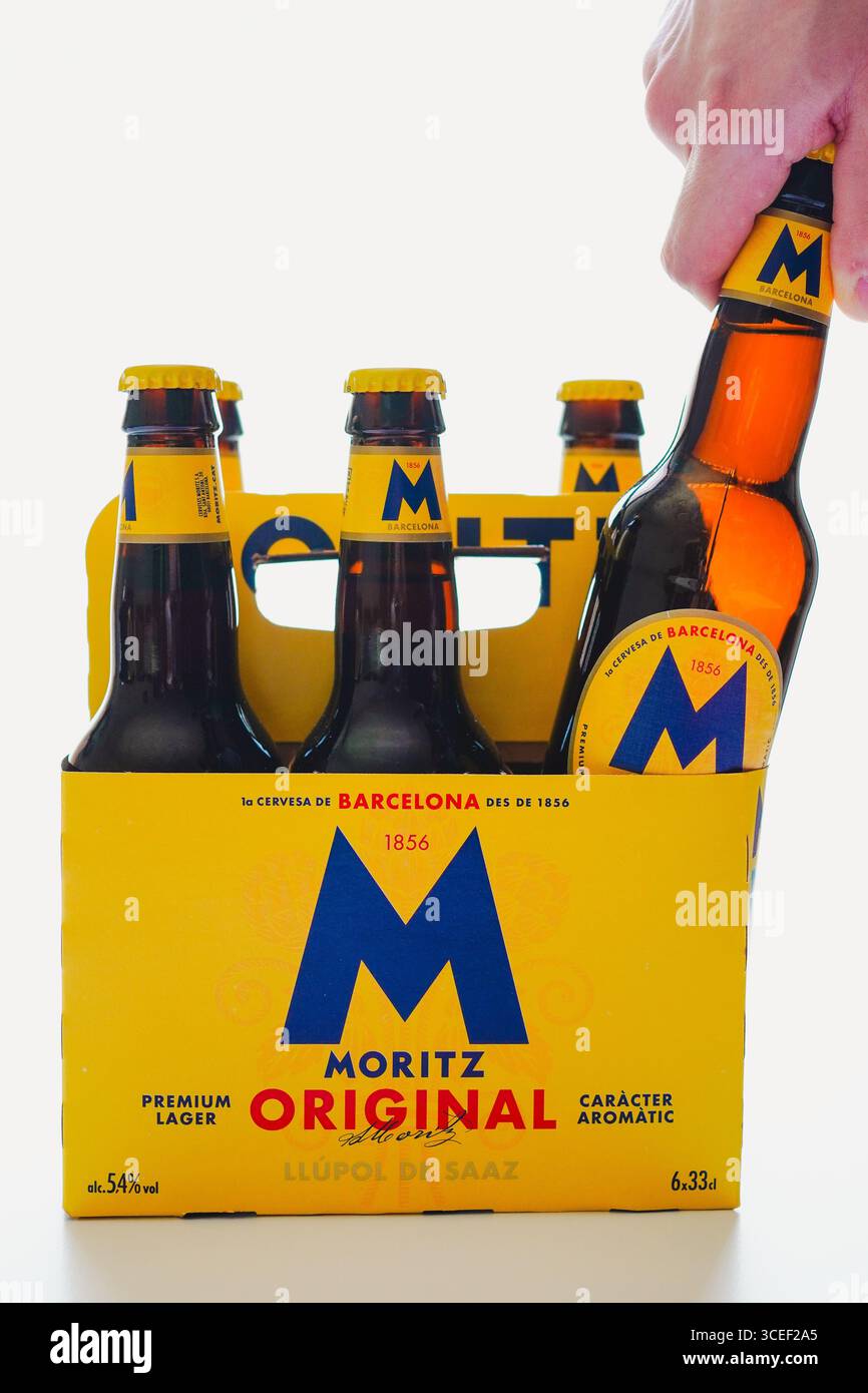 Barcelone, Espagne - 7 Augusto 2025, jeune homme prenant une bouteille de bière dans un étui en carton de six paquets sur fond blanc Banque D'Images