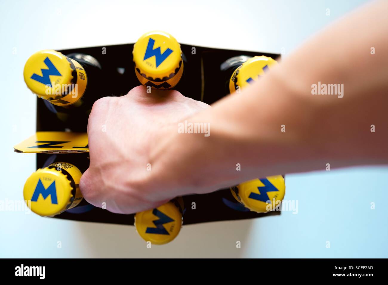 Gros plan d'un jeune homme portant un étui en carton de six paquets sur fond blanc Banque D'Images