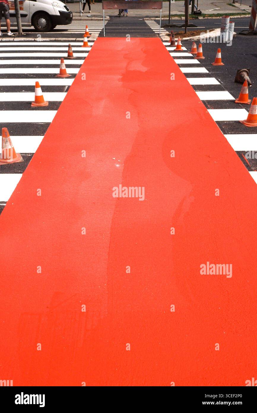 Tapis rouge. Un passage fraîchement peint avec des cônes de circulation et un accent sur la piste cyclable rouge, photographié avec un film Olympus Mju et Kodak. Banque D'Images