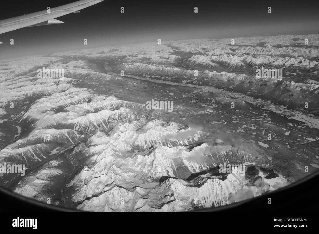 Vue aérienne des montagnes Rocheuses canadiennes recouvertes de neige vues depuis un siège hublot d'avion alors qu'il survolait l'aile de l'avion de l'ouest du Canada en haut à gauche Banque D'Images