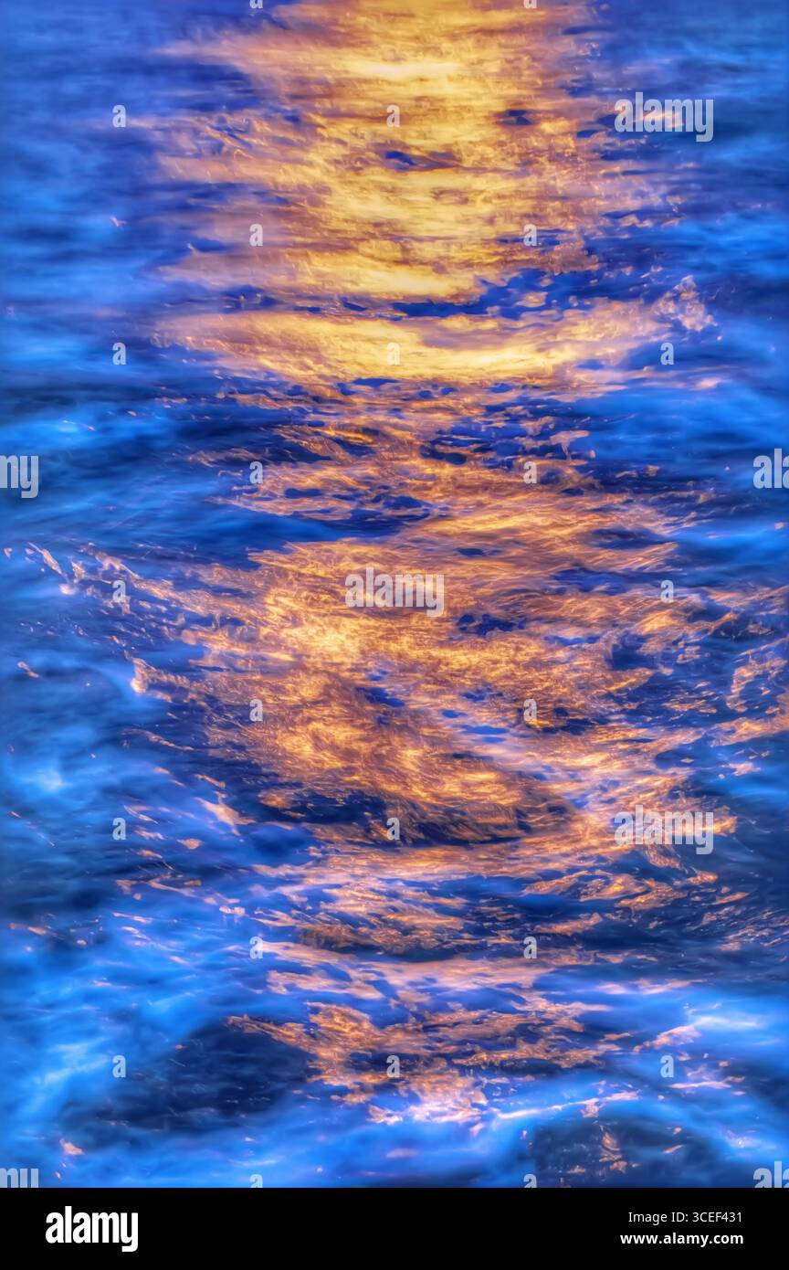 Lumière dorée du soleil couchant projetant une lueur chaude sur l'eau bleue fraîche et dynamique Banque D'Images