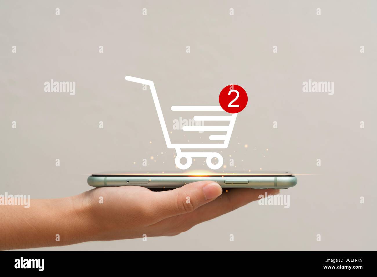 Une main humaine tenant un smartphone avec une icône de panier lumineux et un symbole de notification, représentant les achats en ligne, le commerce électronique, le marché numérique Banque D'Images
