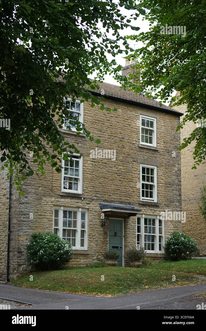 Maison historique en pierre avec jardin luxuriant entouré d'arbres verts. Chipping Norton, Angleterre Banque D'Images