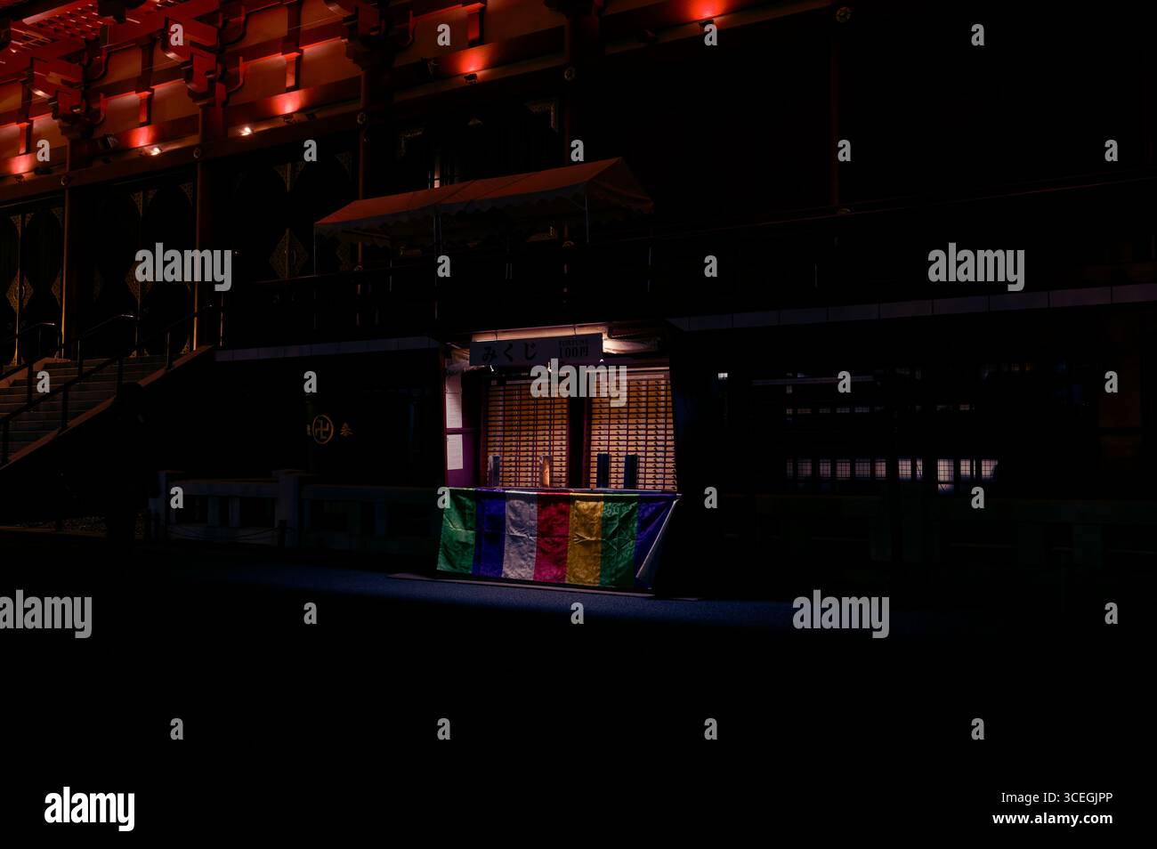 Une stalle solitaire révélatrice de fortune au temple Sensō-ji brille doucement la nuit, drapée de couleurs bouddhistes de prière Banque D'Images