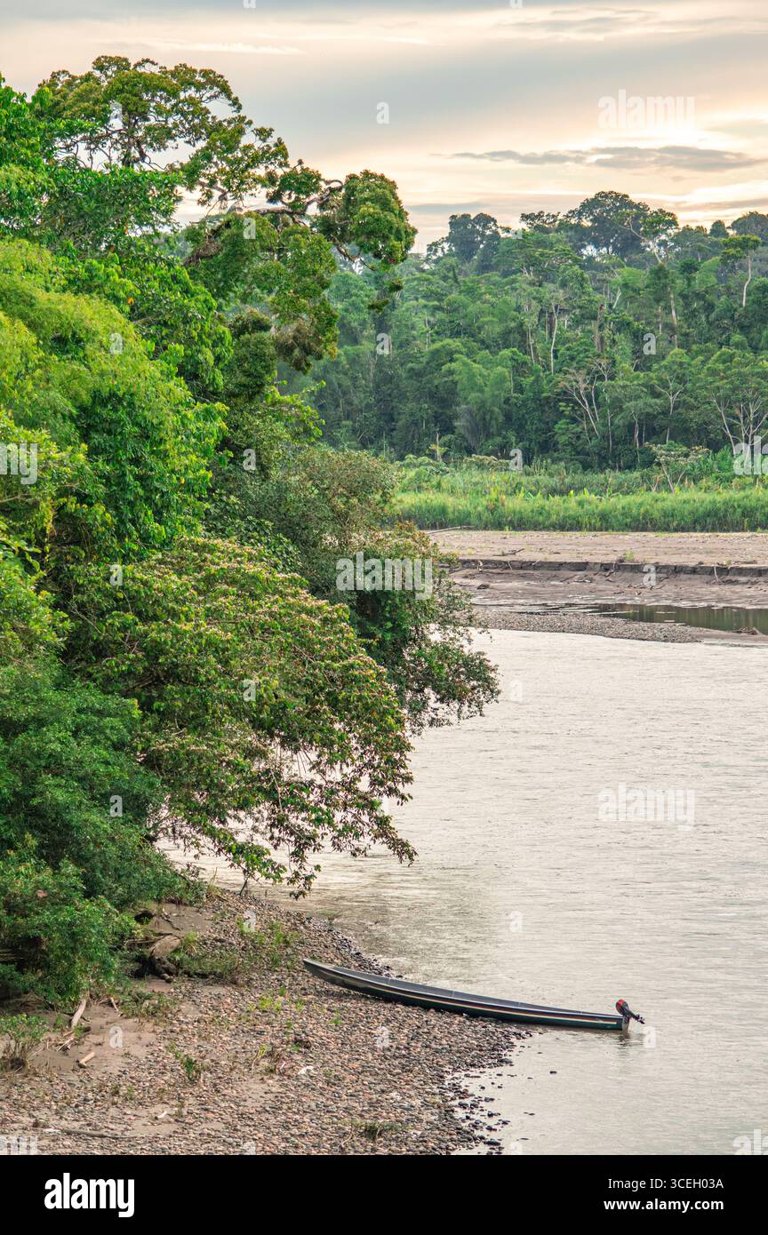 Une scène fluviale tranquille à Putumayo, en Colombie, avec une végétation luxuriante et un petit bateau le long du rivage. Banque D'Images