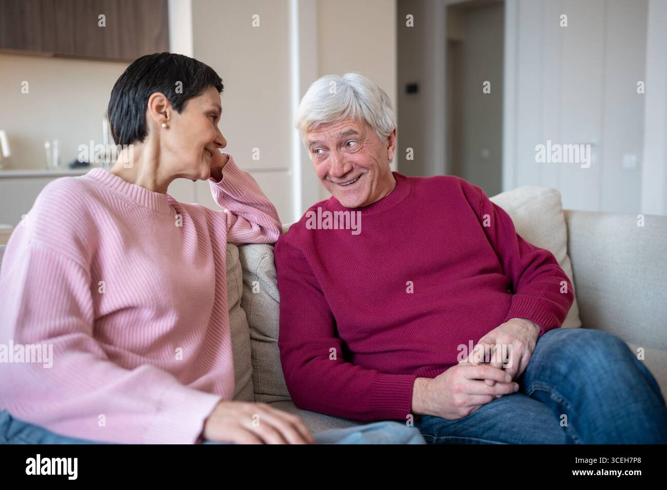 Heureuse vie conjugale de famille aînée. Mari souriant partager des histoires avec une femme attentive sur le canapé à la maison Banque D'Images