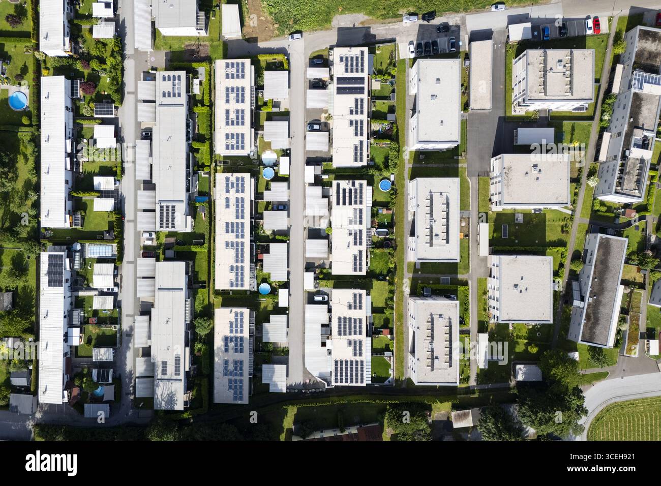 Vue aérienne de rangées soignées de bâtiments prélassés au soleil, panneaux solaires étincelants, dans un cadre verdoyant dans un quartier résidentiel animé, Peggau-Deutschfeistritz, Styrie, Autriche. Banque D'Images