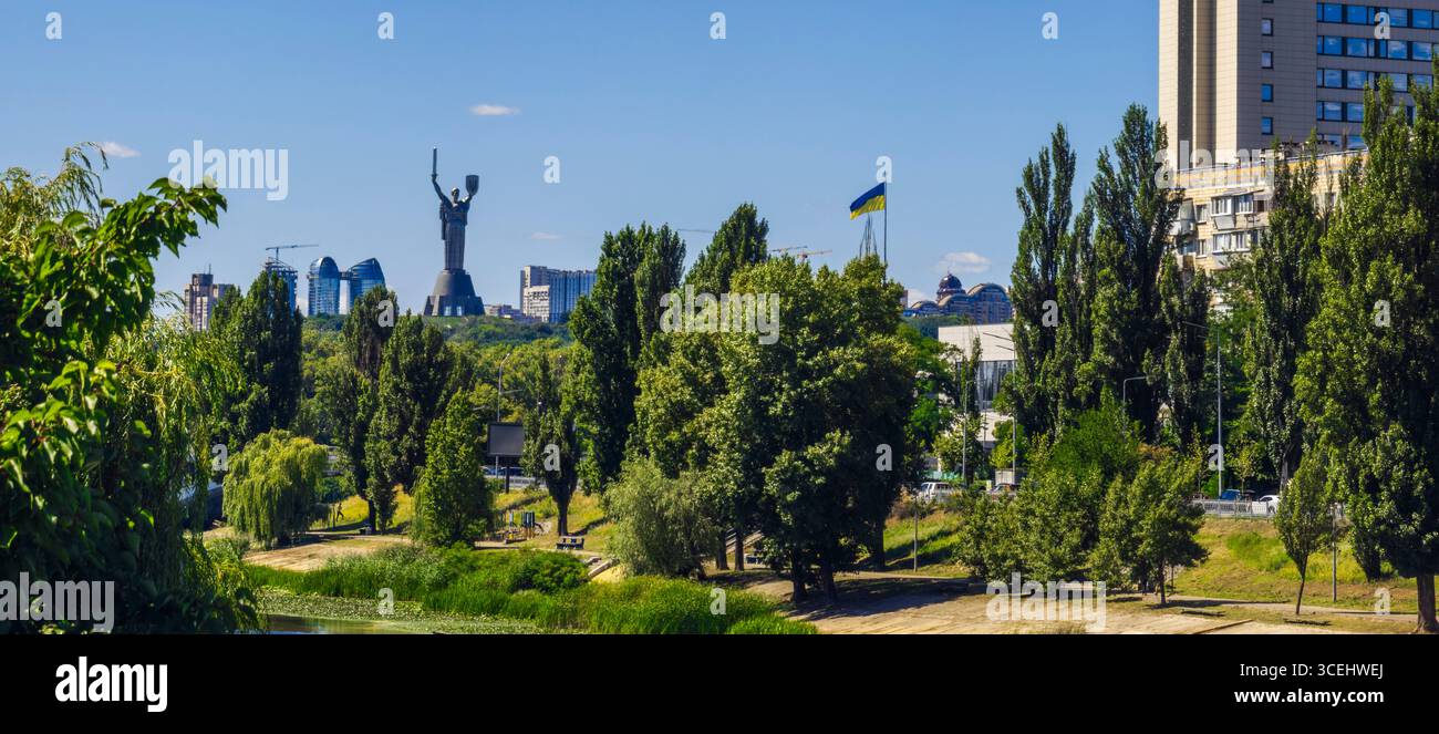 Des arbres verdoyants et le canal de la rivière Dnipro encadrent le monument emblématique de mère Ukraine, un symbole de l'identité nationale ukrainienne, dans un contexte de Banque D'Images