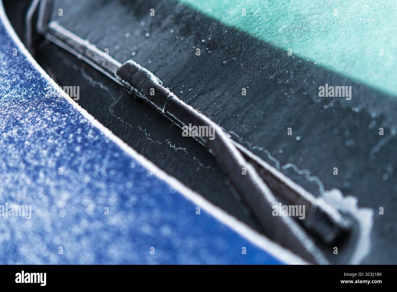Givre enduit l'essuie-glace d'une voiture garée à l'extérieur par un matin froid d'hiver. La scène capture la beauté du temps glacial et des teintes hivernales. Banque D'Images Givre enduit l'essuie-glace d'une voiture garée à l'extérieur par un matin froid d'hiver. La scène capture la beauté du temps glacial et des teintes hivernales. Banque D'Images