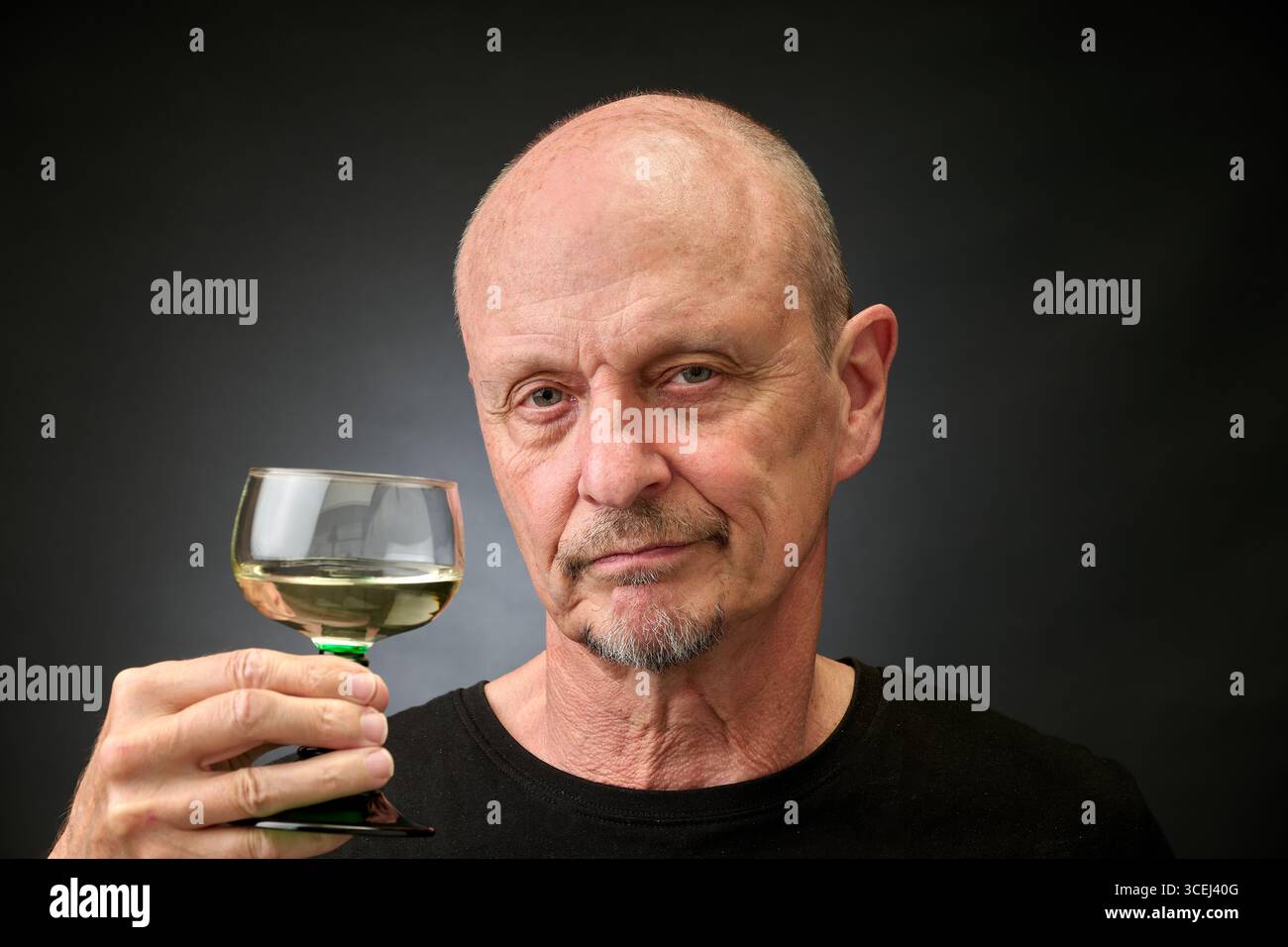 Gros plan portrait d'un homme senior dégustant un bon vin blanc dans un éclairage vintage de style Harcourt Banque D'Images