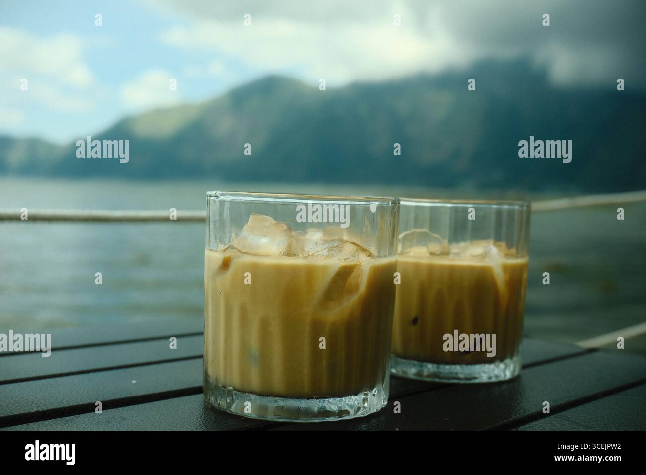 Deux verres de café latte glacé avec vue directe sur le lac et les montagnes Banque D'Images Deux verres de café latte glacé avec vue directe sur le lac et les montagnes Banque D'Images