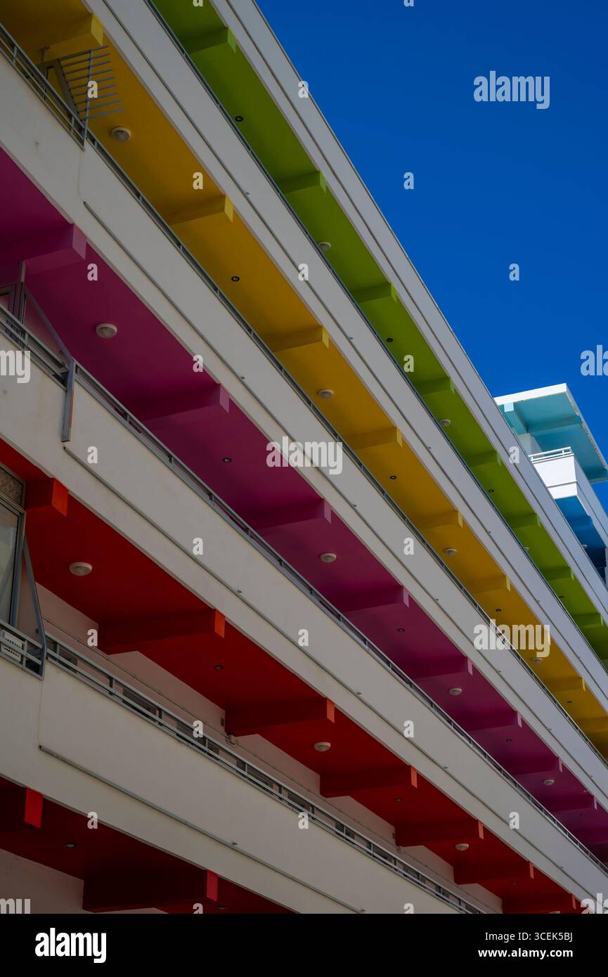 Un bâtiment avec une façade arc-en-ciel en arrière-plan. Le bâtiment a les couleurs vert, jaune, rose, rouge, avec un encadrement vertical. Banque D'Images