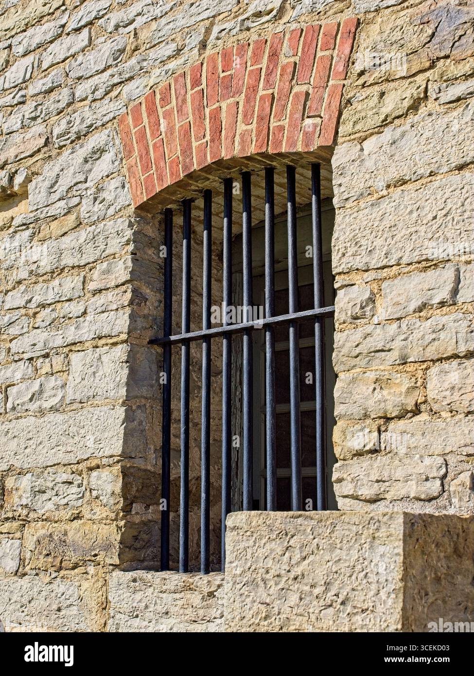 Murs épais en maçonnerie calcaire avec fenêtre voûtée en brique barrée ouvrant sur le bâtiment du commissariat du lieu historique national du Fort Smith Banque D'Images