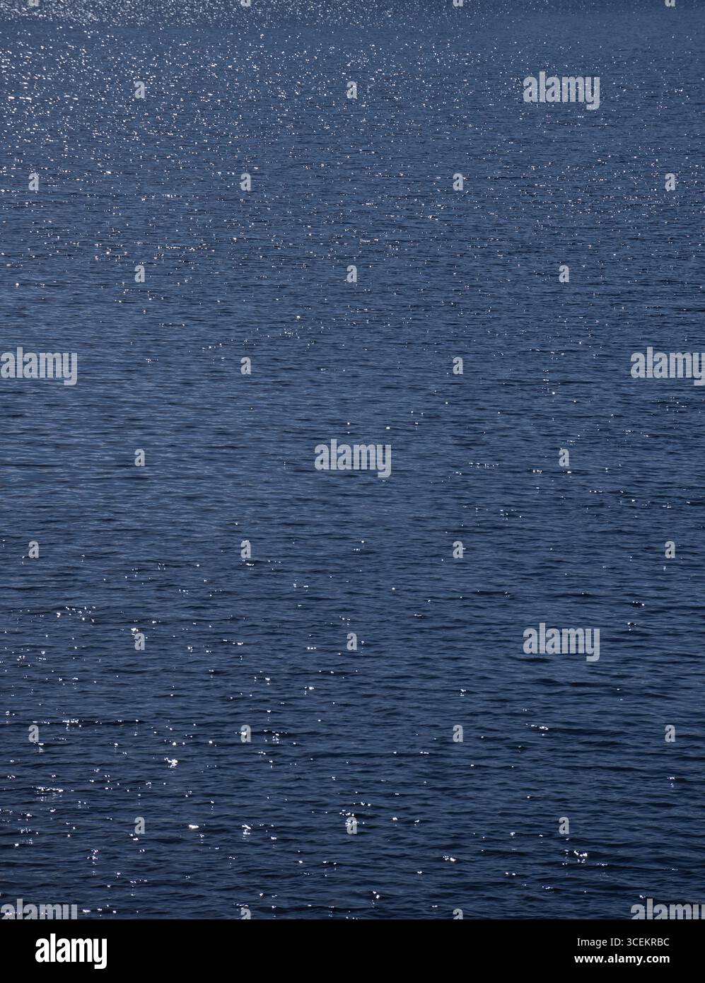 gros plan de l'eau sur un lac avec le soleil scintillant sur l'eau bleue créant des étincelles de blanc brillant sur la surface lors d'une belle journée d'été Banque D'Images