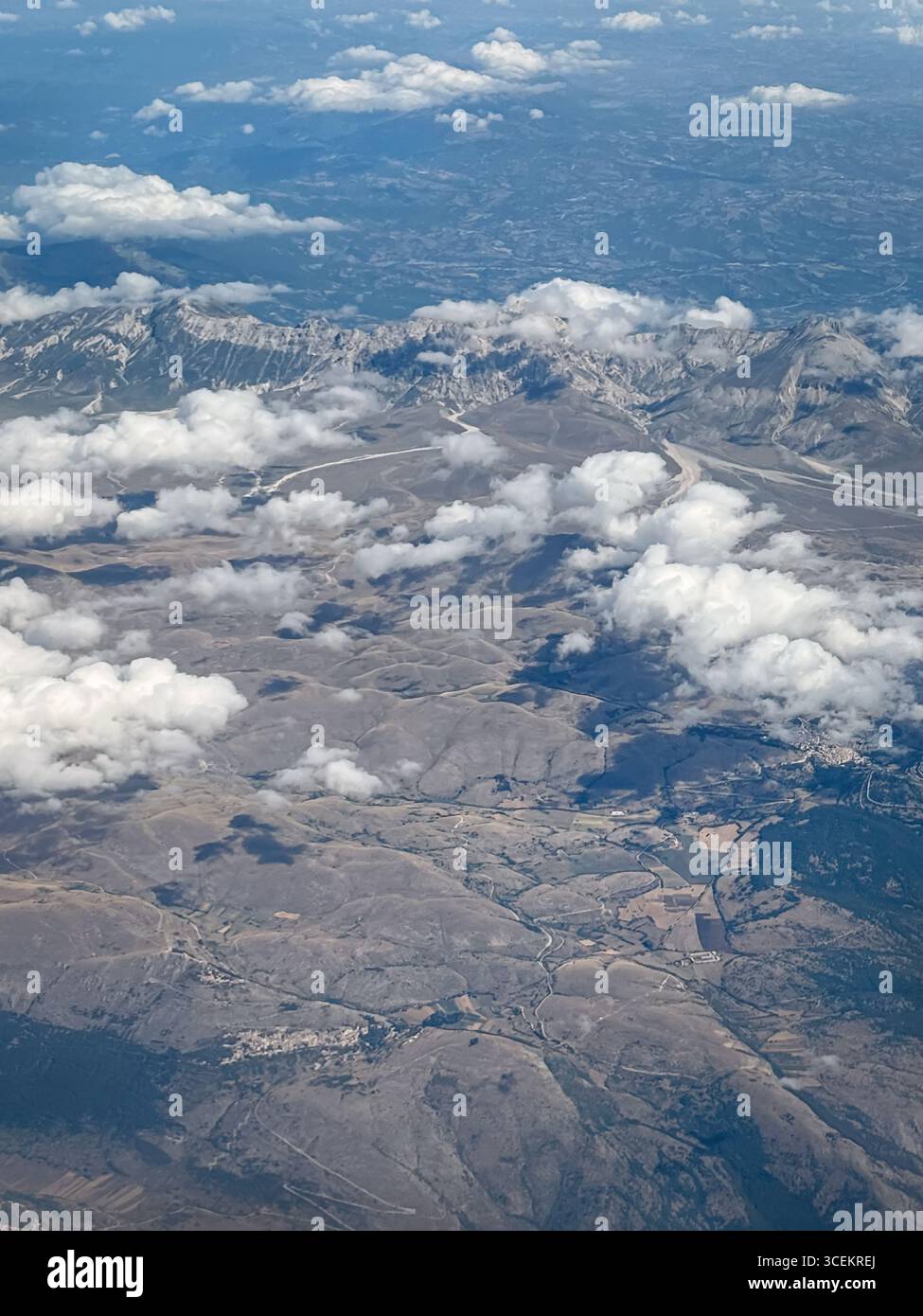 Vue aérienne de haute altitude montre un paysage accidenté et montagneux parsemé de parcelles de petits villages et de routes serpentant à travers les vallées. Fluf Banque D'Images