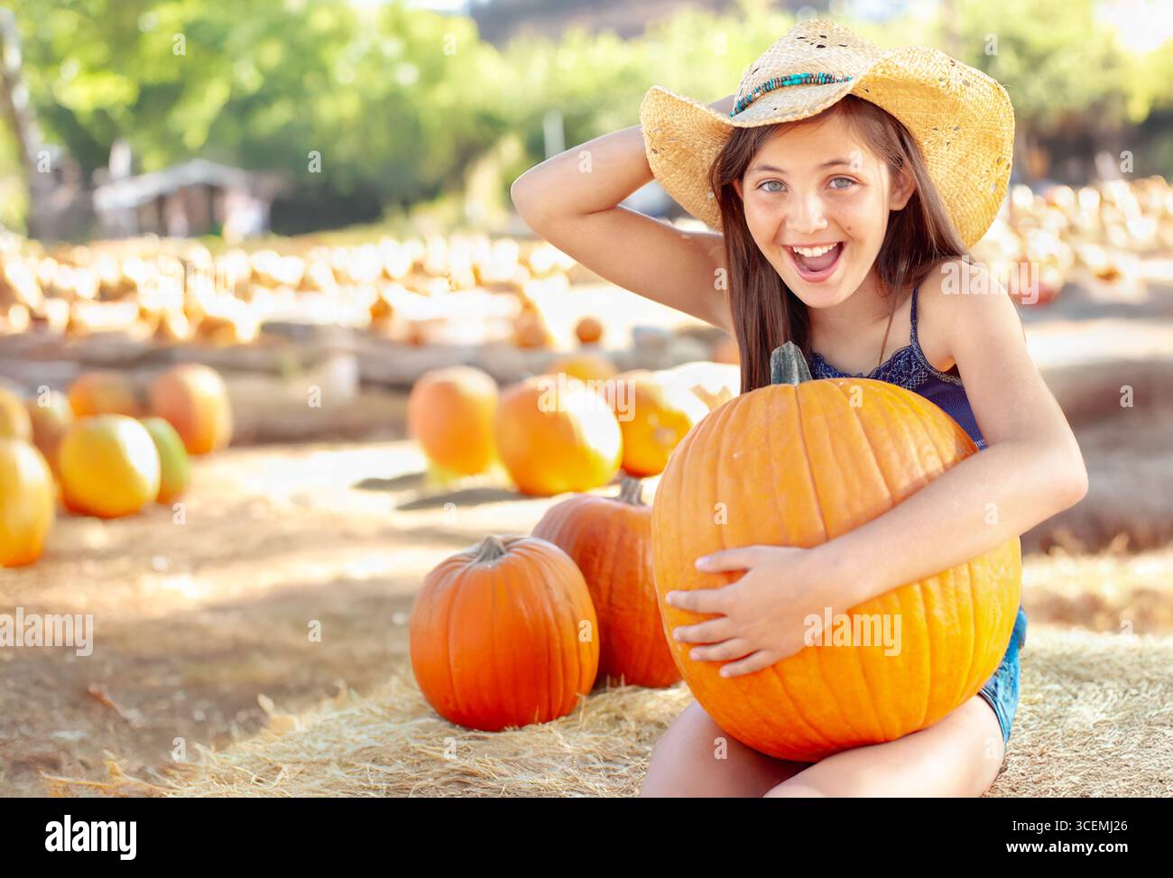 Jolie fille portant un chapeau de cowboy appréciant le Patch de citrouille sur un jour d'automne ensoleillé. Banque D'Images
