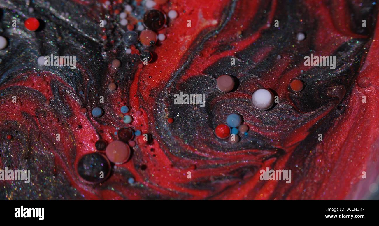 Débit d'huile. Fond liquide. Encre de couleur bleu rouge défocalisé dans une texture ronde d'eau scintillante flottant sur l'abstraction noire sombre créative. Banque D'Images