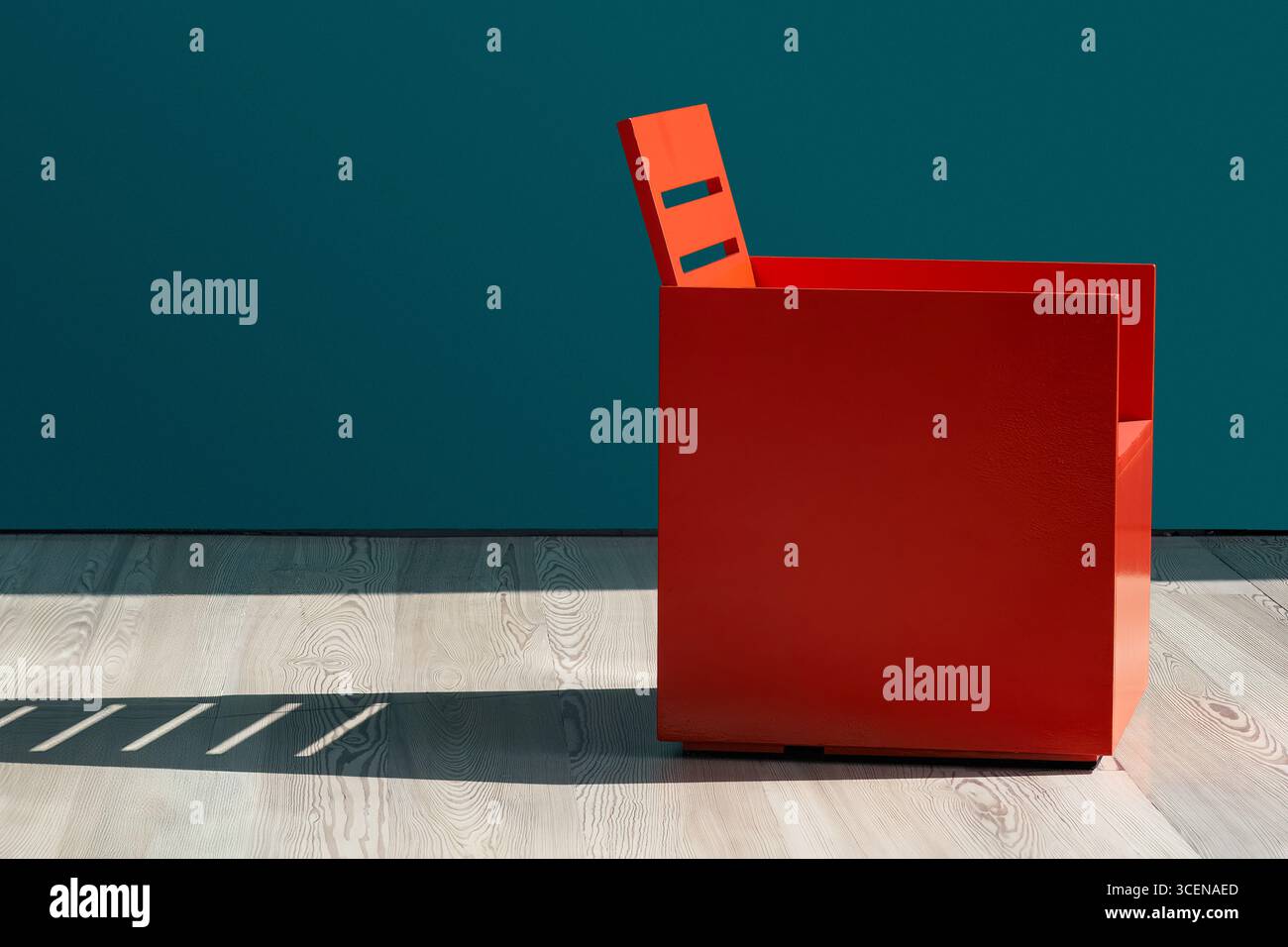 Chaise rouge de profil devant un mur bleu vert, projetant une longue ombre. Minamalist. Copier l'espace. Banque D'Images