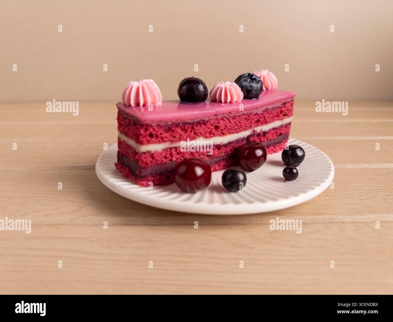 Photo rapprochée d'un gâteau éclatant à l'arôme des baies avec glaçage rose, décoré de crème fouettée, de cerises et de myrtilles. Servi sur un pl blanc Banque D'Images