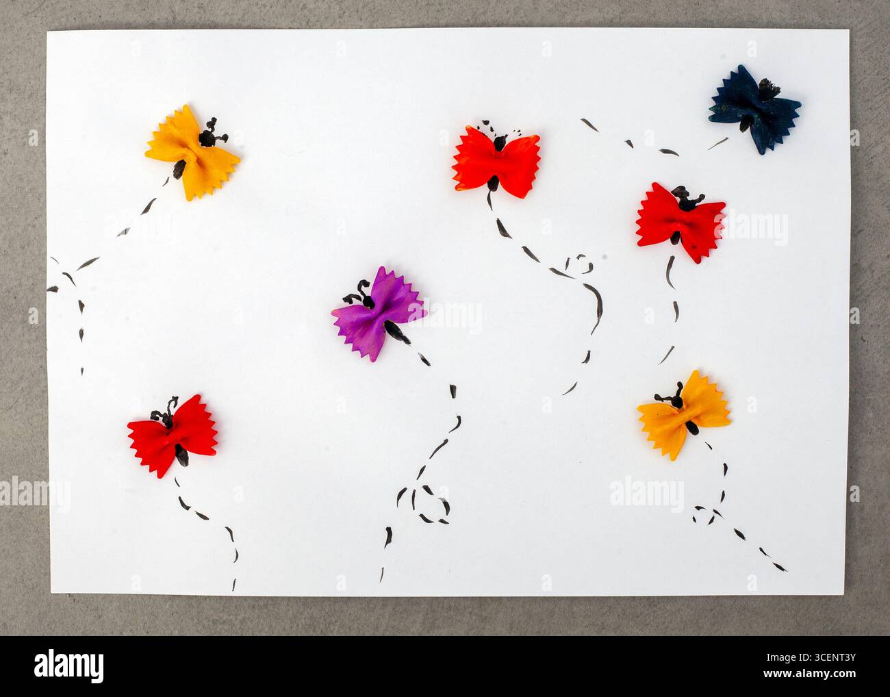 Dessin de papillons à base de pâtes alimentaires. Les papillons sont de différentes couleurs et sont dispersés sur le papier. Le dessin transmet un sens de W. Banque D'Images