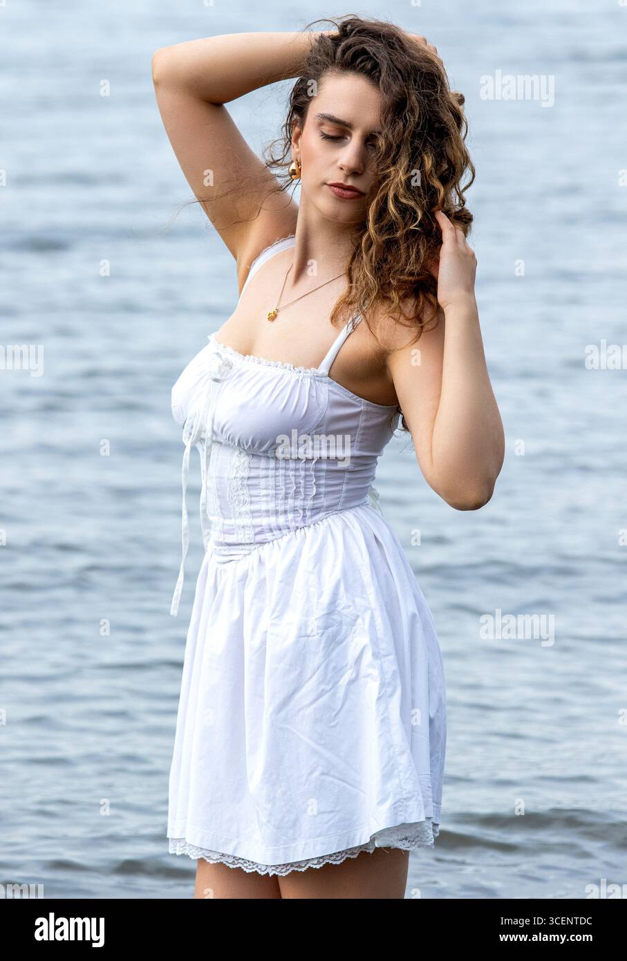 Tayport à Fife, en Écosse. Femme à la mode portant une robe blanche courte se tient dans la rivière Tay lors d'une séance photo sur le thème de la fantaisie l'après-midi, Royaume-Uni Banque D'Images