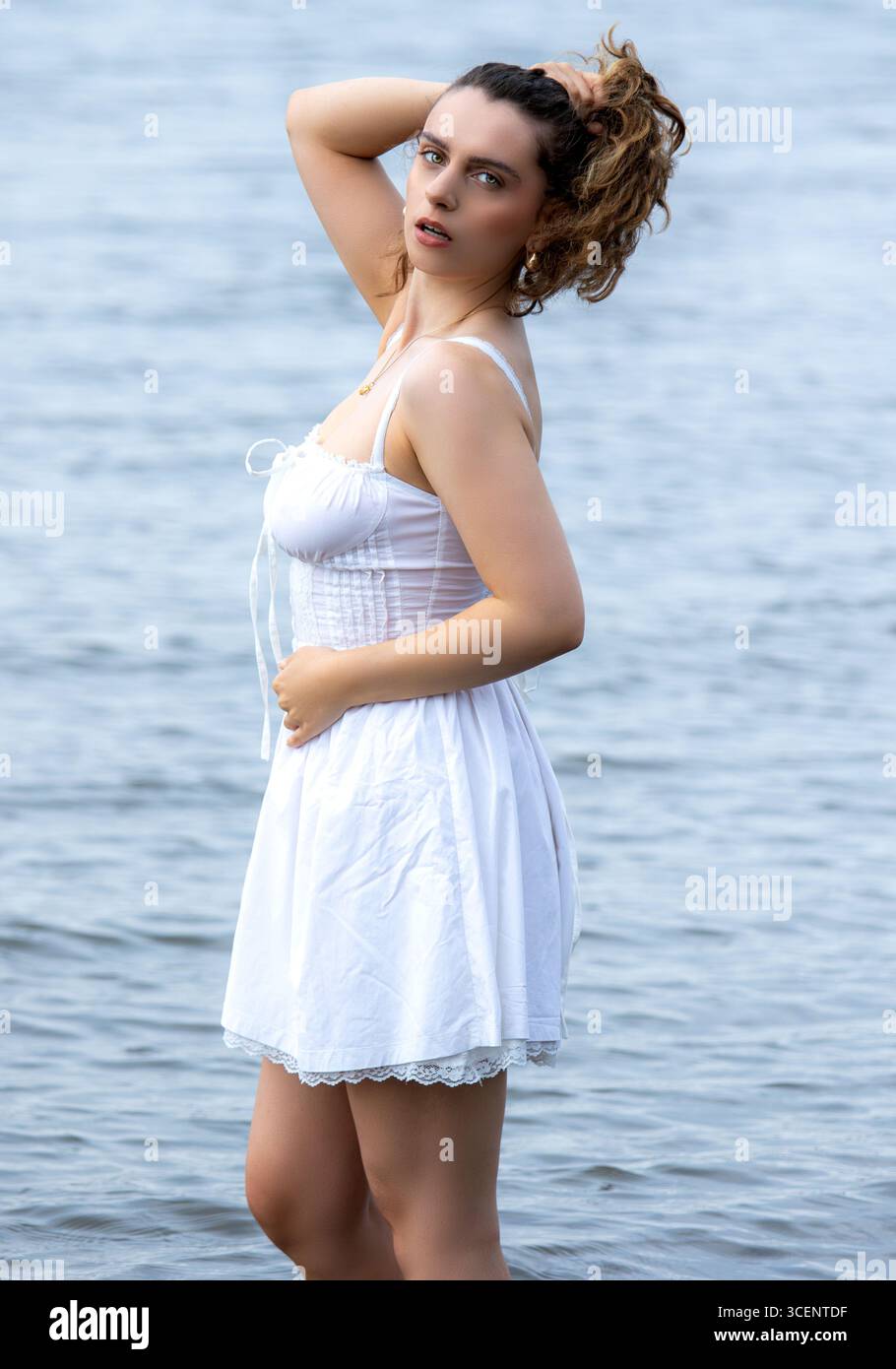 Tayport à Fife, en Écosse. Femme à la mode portant une robe blanche courte se tient dans la rivière Tay lors d'une séance photo sur le thème de la fantaisie l'après-midi, Royaume-Uni Banque D'Images