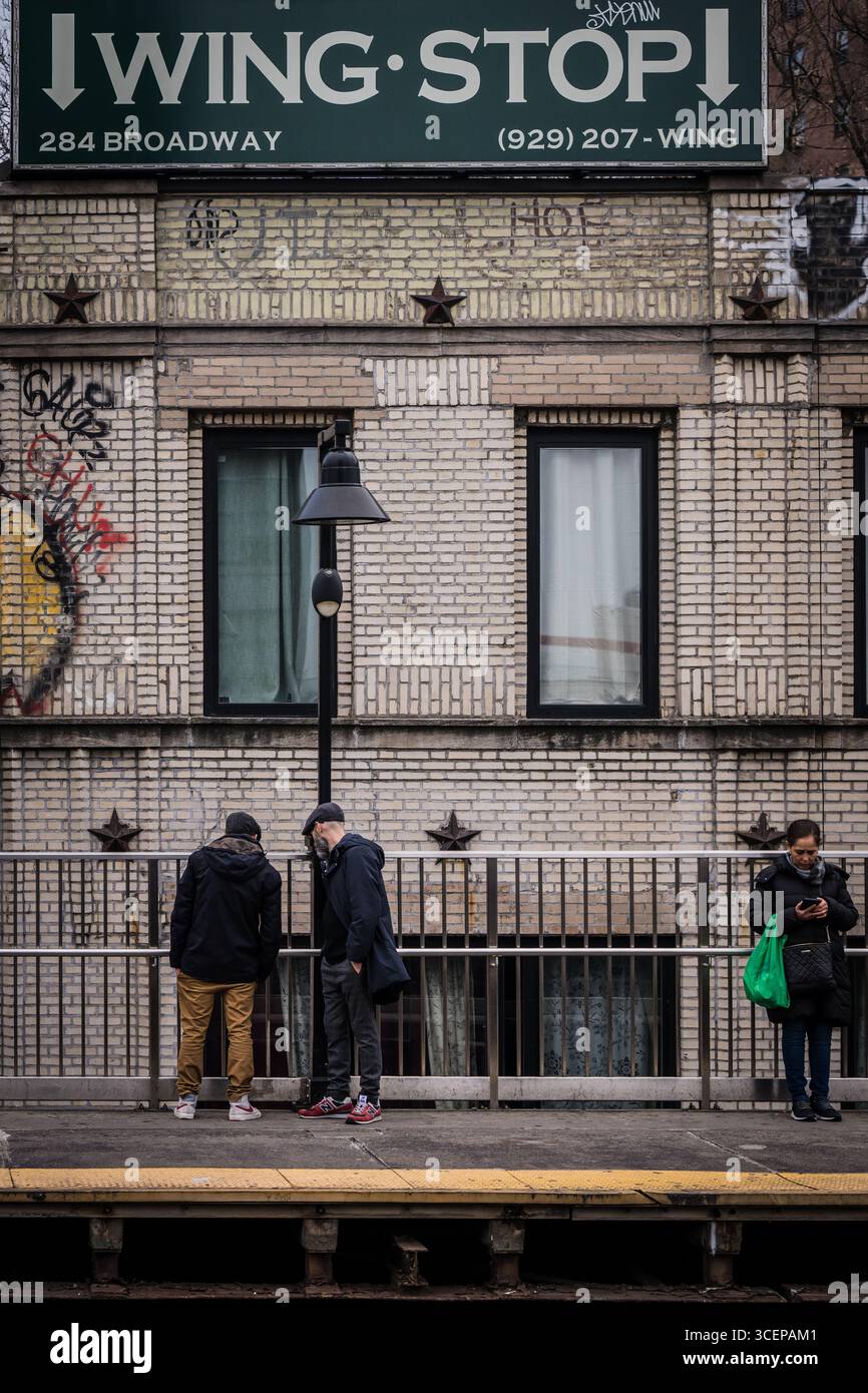 New York, États-Unis - 25 décembre 2023 : vue du panneau Wingstop au sommet d'une station de métro, où les personnages se dressent silhouettés contre la façade texturée et carrelée. Banque D'Images