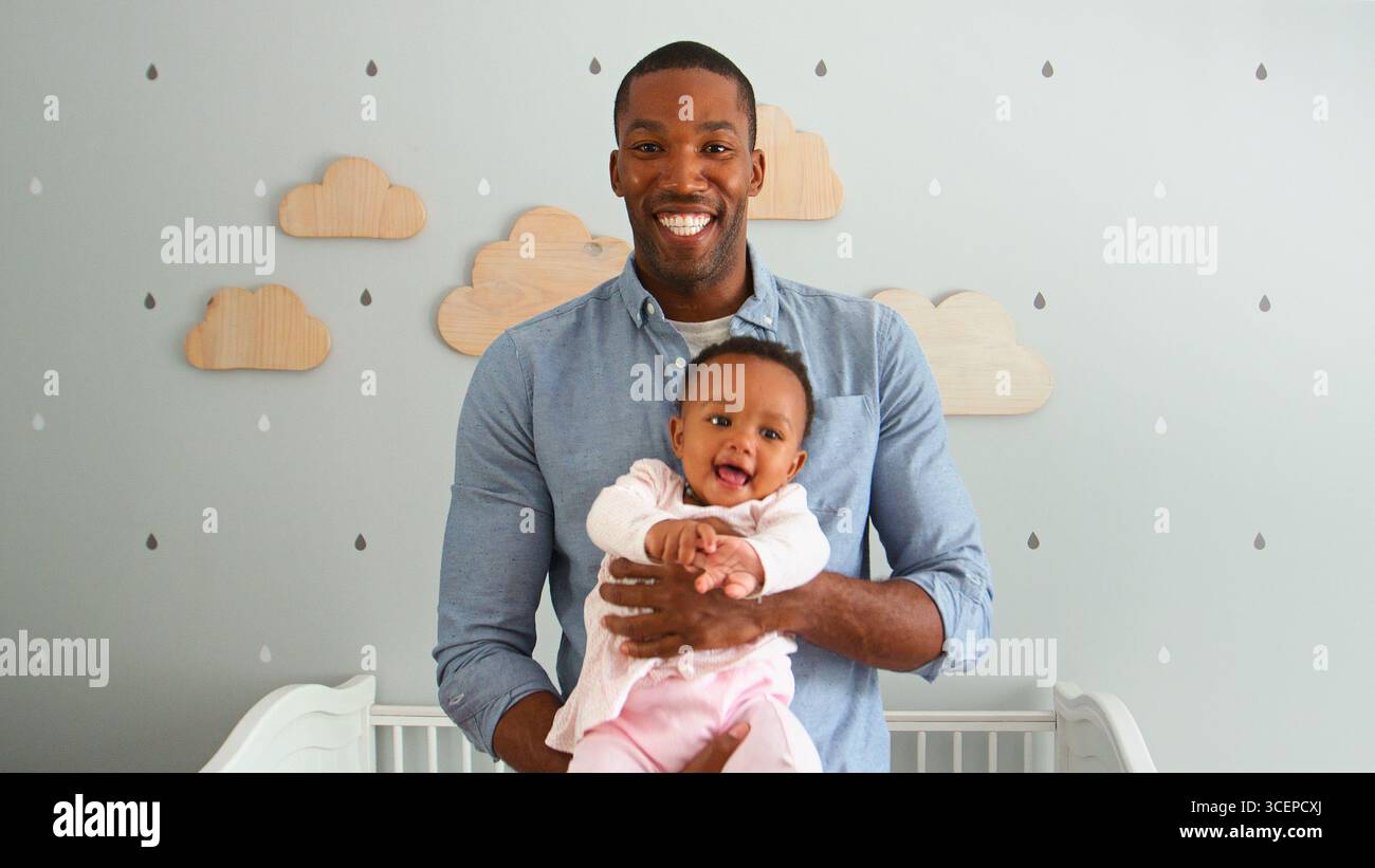 Portrait de Père Cuddling bébé fille dans la pépinière décorée de nuages Banque D'Images