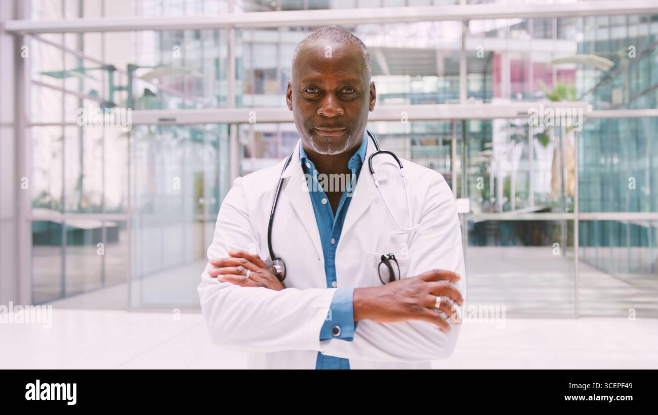 Portrait d'un médecin masculin senior portant un manteau blanc debout dans le bâtiment moderne de l'hôpital Banque D'Images