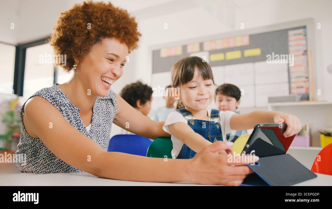 Enseignant avec une élève de l'école élémentaire féminine utilisant la tablette numérique dans la classe STEM Banque D'Images