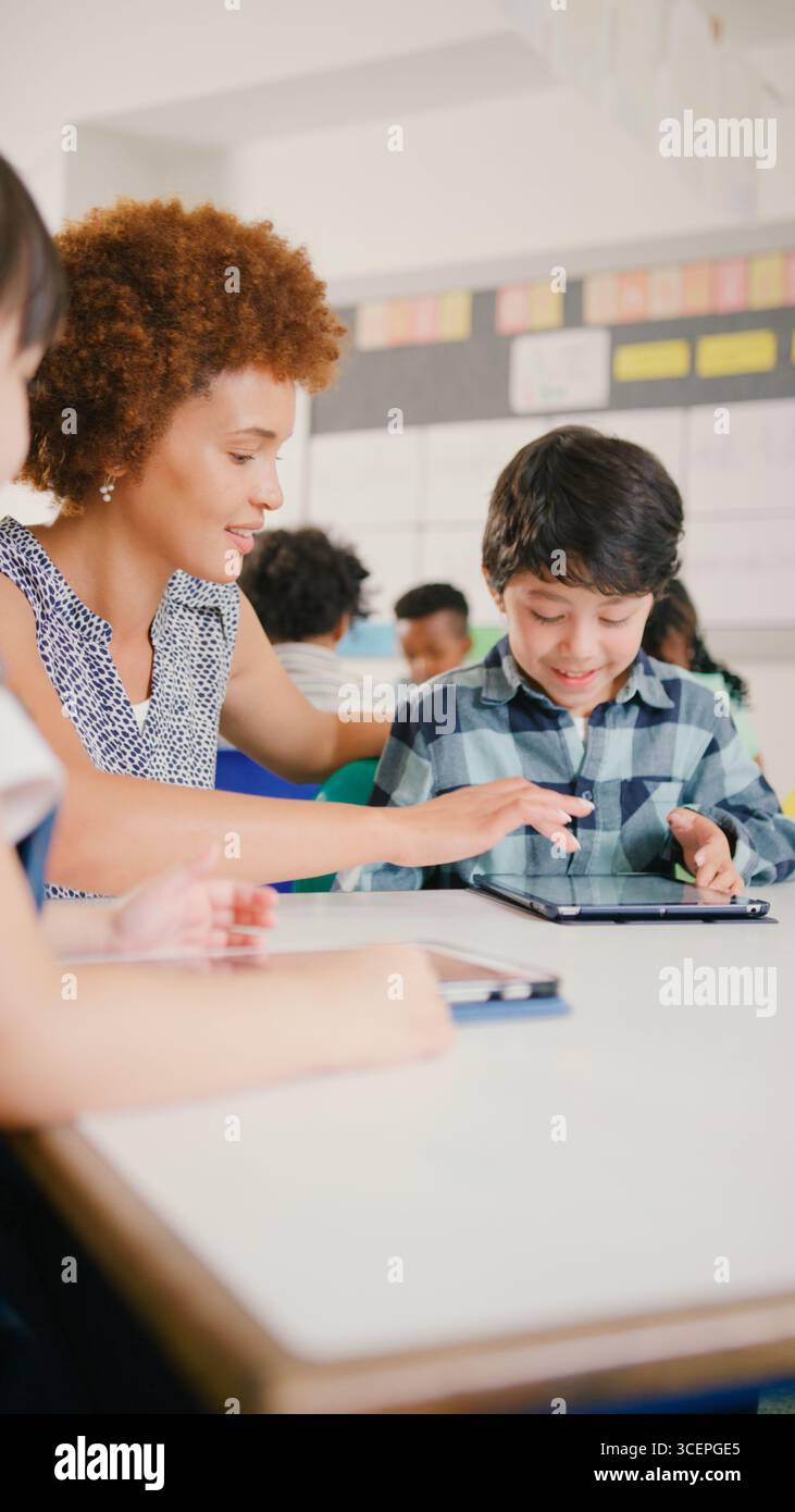 Enseignante avec des élèves de l'école primaire utilisant la tablette numérique dans la classe STEM Banque D'Images