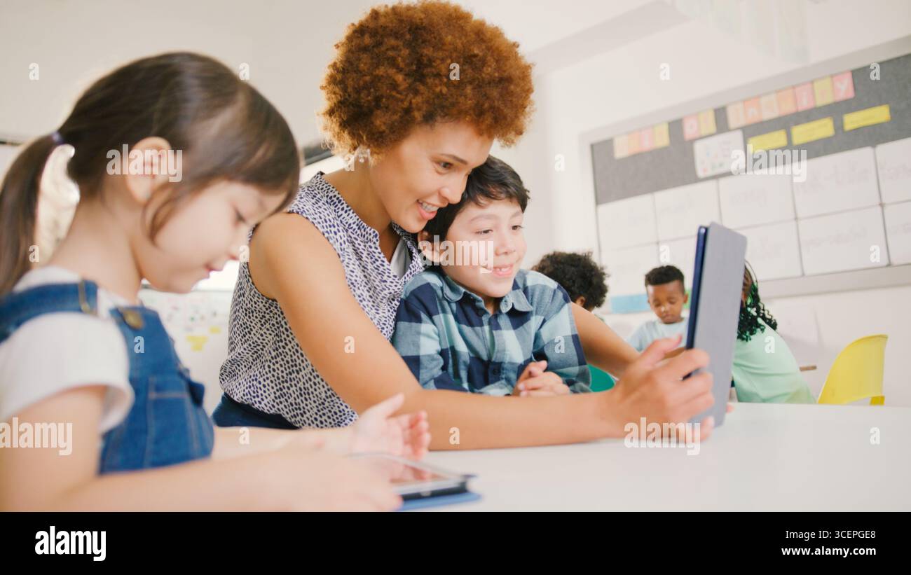 Enseignante avec des élèves de l'école primaire utilisant la tablette numérique dans la classe STEM Banque D'Images
