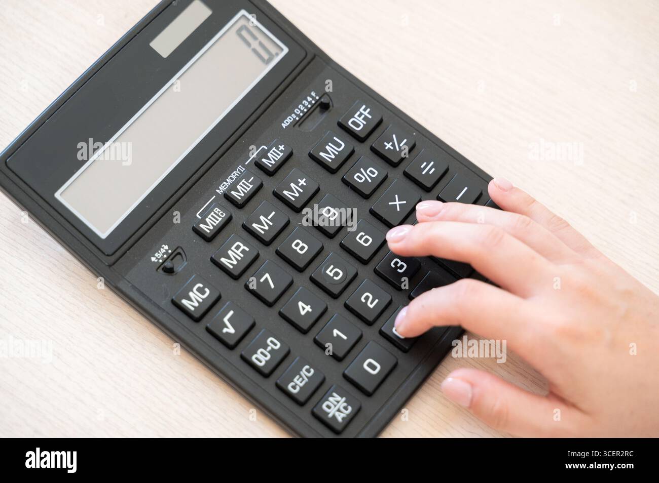 Une vue rapprochée intime montrant une main appuyant sur les boutons d'une calculatrice, parfait pour les thèmes de la finance et de l'éducation Banque D'Images