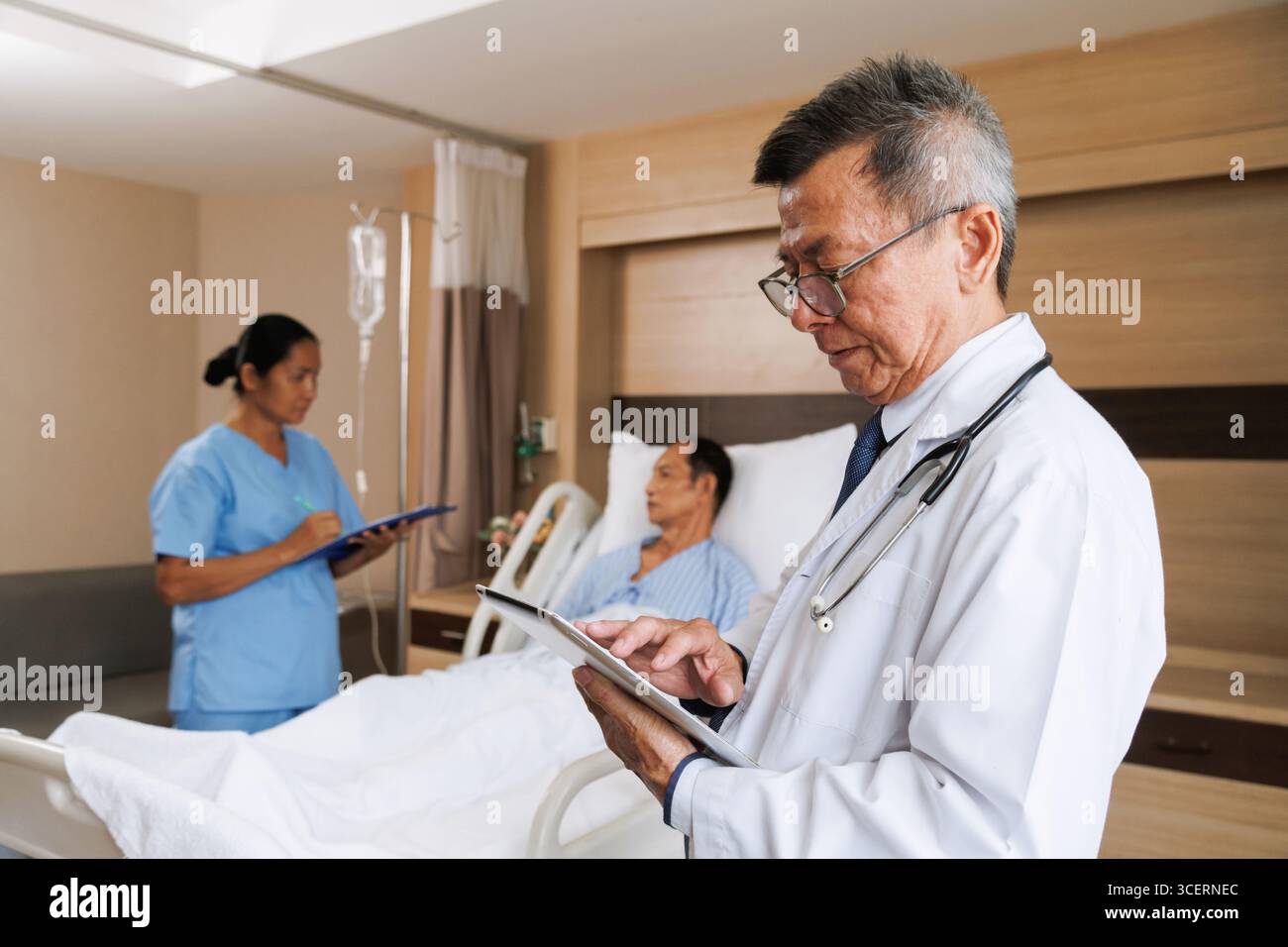 médecin professionnel masculin senior asiatique utilisant la tablette pour le dossier de santé numérique et l'infirmière écrit des notes à côté du patient. chambre d'hôpital équipée médicale in Banque D'Images médecin professionnel masculin senior asiatique utilisant la tablette pour le dossier de santé numérique et l'infirmière écrit des notes à côté du patient. chambre d'hôpital équipée médicale in Banque D'Images
