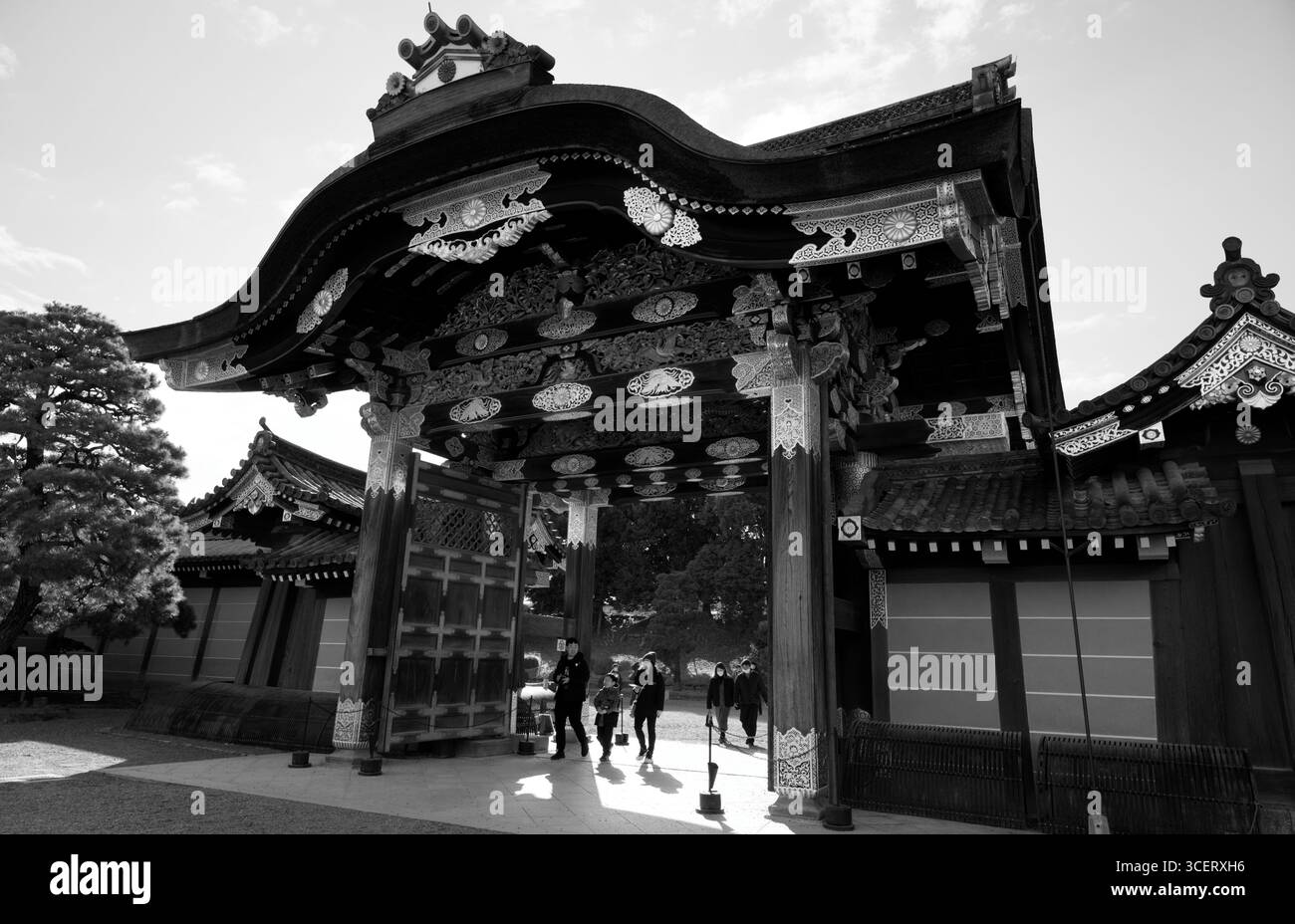 Les visiteurs marchent sous la porte Karamon ornée du château de Nijo à Kyoto en noir et blanc Banque D'Images