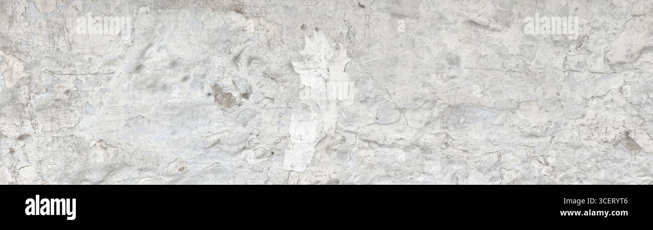 Vue rapprochée d'un mur en béton blanc altéré, révélant une surface texturée avec des fissures, une décoloration et une peinture écaillée, créant une tapisserie abstraite Banque D'Images