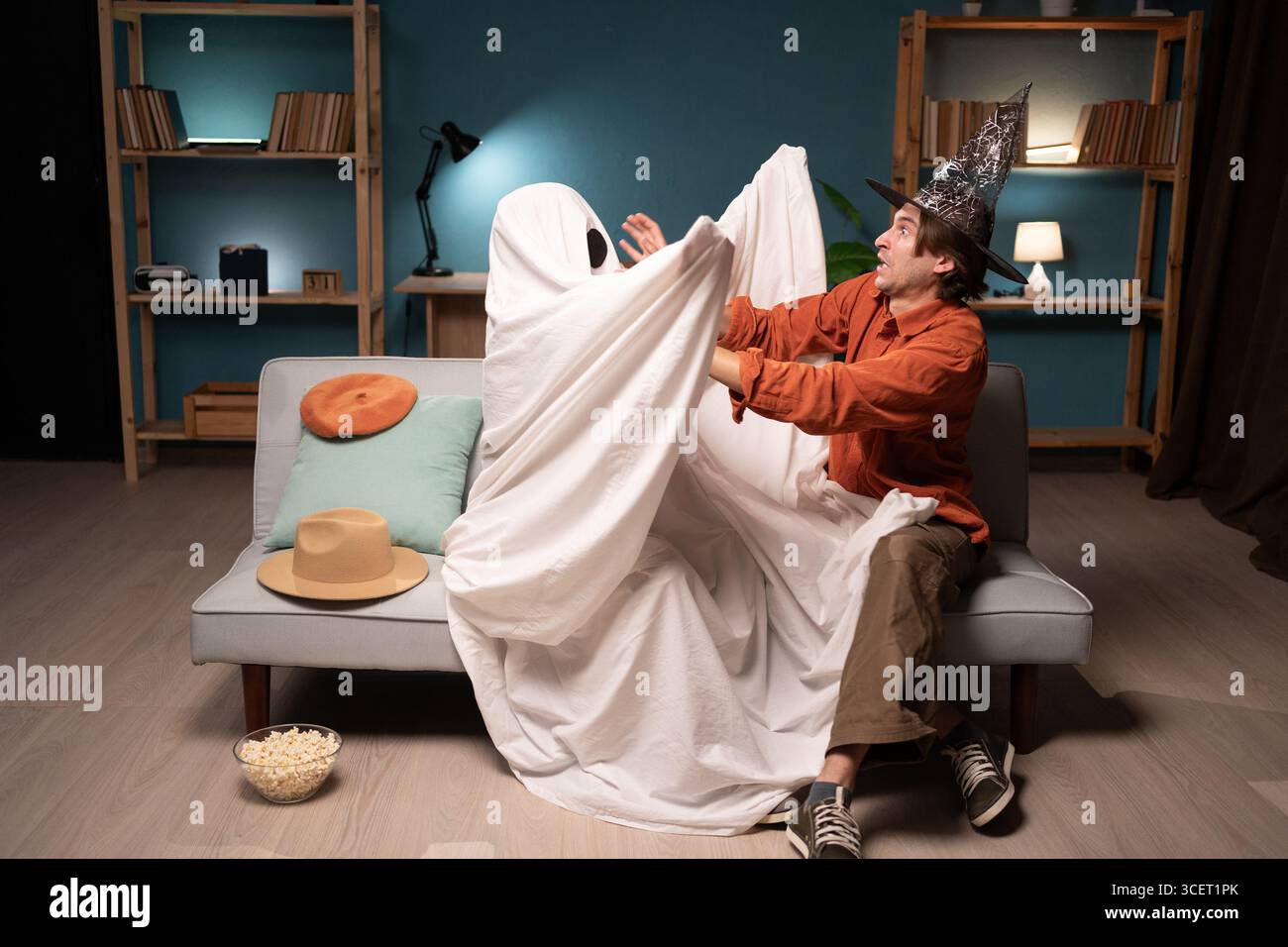 Homme et personne méconnaissable en costume de fantôme avec des yeux noirs s'amusant à la maison pendant la veille d'Halloween. Moment effrayant mais joyeux. Fête effrayante Banque D'Images