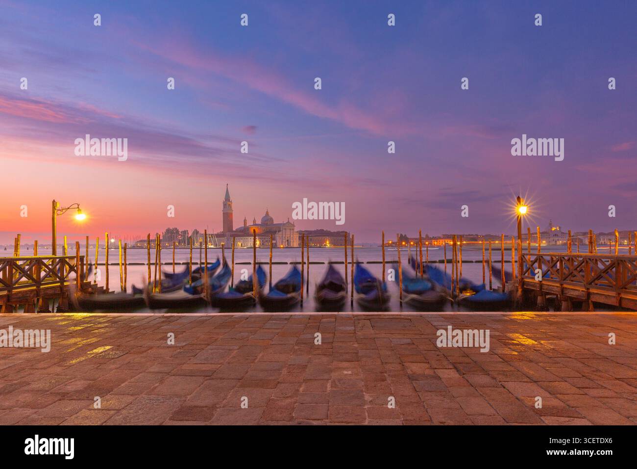 Vue sur l'île San Giorgio Maggiore et les gondoles amarrées au lever du soleil à Venise Italie Banque D'Images