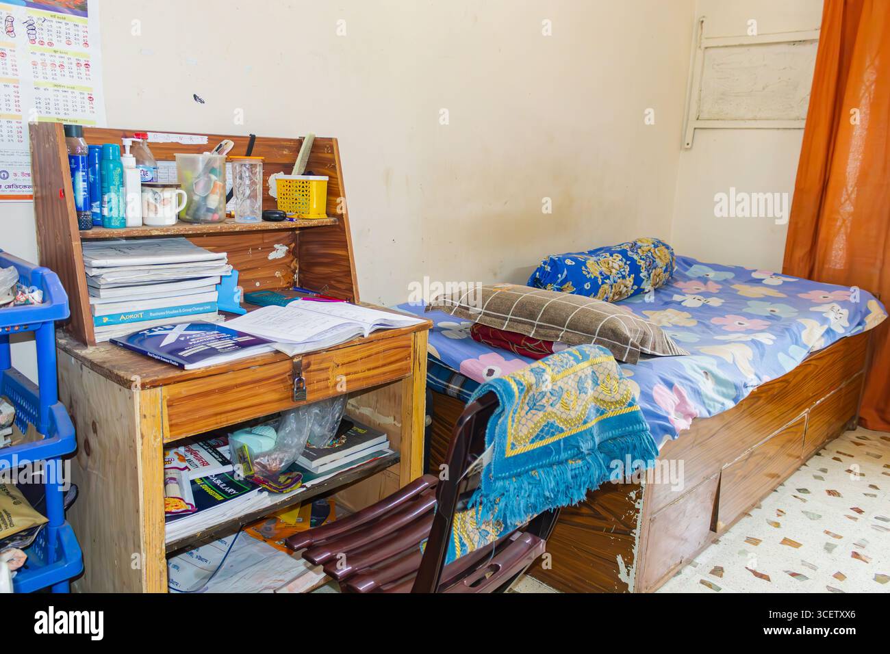 Bureau fonctionnel en bois avec étagère ouverte et essentiels à côté du lit dans un espace de vie compact Banque D'Images