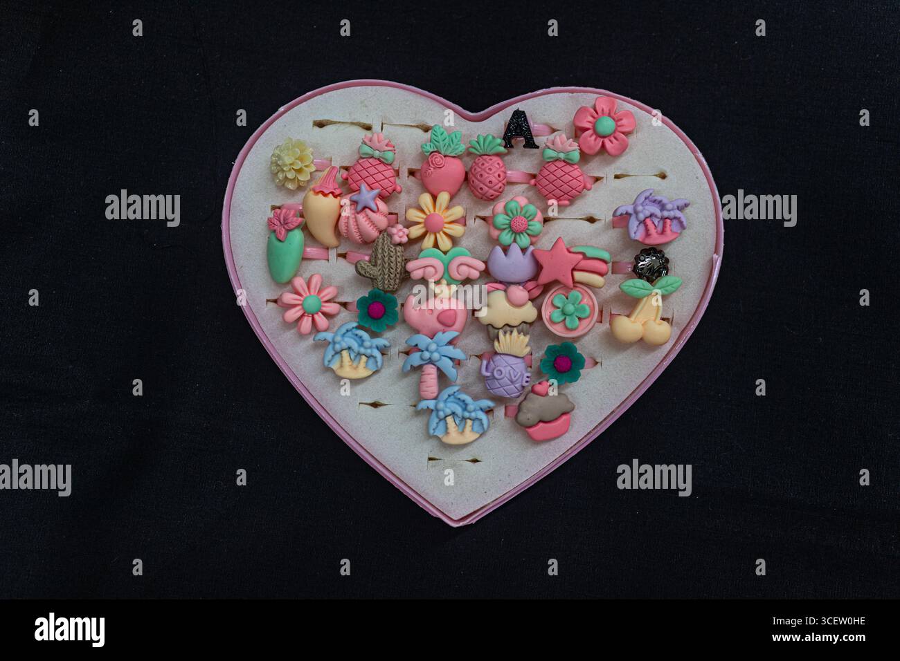 Adorables anneaux de jouets de couleur pastel pour les enfants présentés soigneusement dans un conteneur de coeur doublé de mousse Banque D'Images