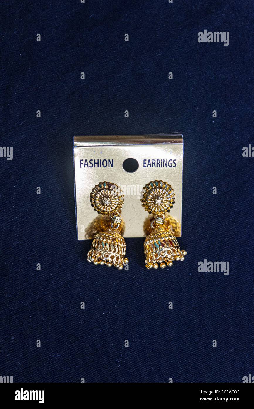 Boucles d'oreilles jhumka dorées brillantes placées sur fond de velours noir pour l'affichage de bijoux traditionnels luxueux Banque D'Images