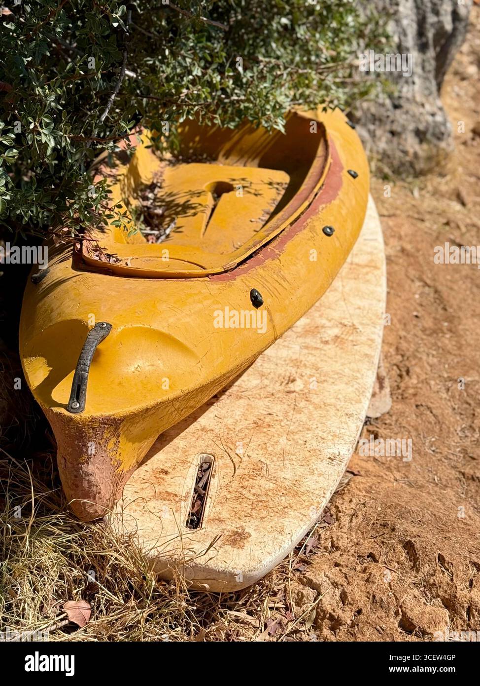 Kayak jaune reposant sur la terre sous un buisson vert, scène estivale extérieure, équipement de kayak, aventure et sports nautiques - Image de stock capturée avec un smartphone