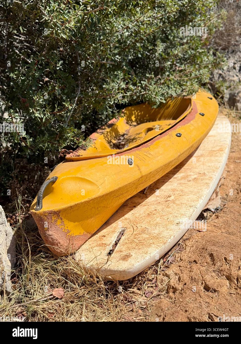 Kayak jaune reposant sur la terre sous un buisson vert, scène estivale extérieure, équipement de kayak, aventure et sports nautiques - Image de stock capturée avec un smartphone