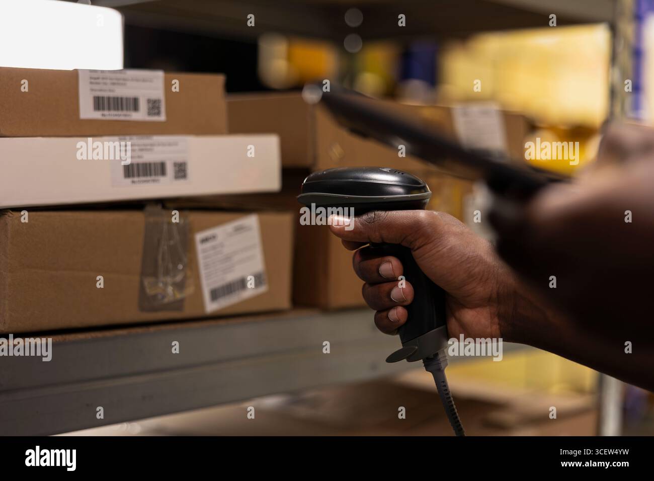 Membre du personnel noir utilisant un lecteur de codes-barres pour traiter les étiquettes d'expédition sur les boîtes des racks de stockage industriels. Scanner les étiquettes awb pour le service de suivi des colis avec des informations de suivi, une logistique précise. Banque D'Images