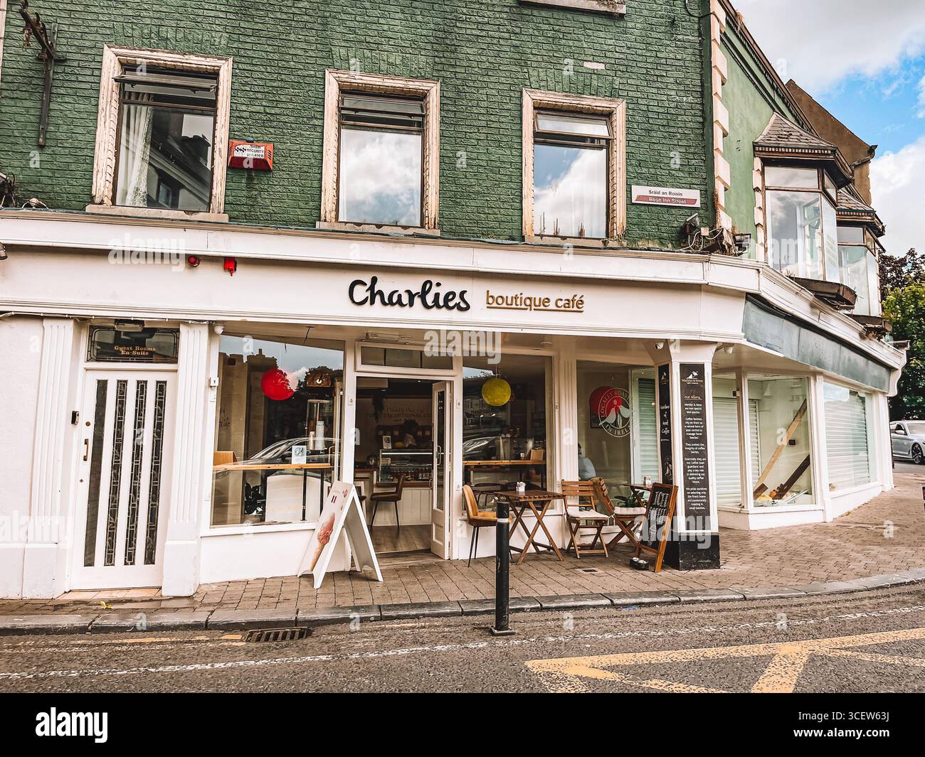 Une petite façade de magasin avec un panneau blanc qui indique « Charities Boutique Cafe ». Le magasin a un extérieur blanc et une façade en briques vertes. Kilkenny Irlande Banque D'Images