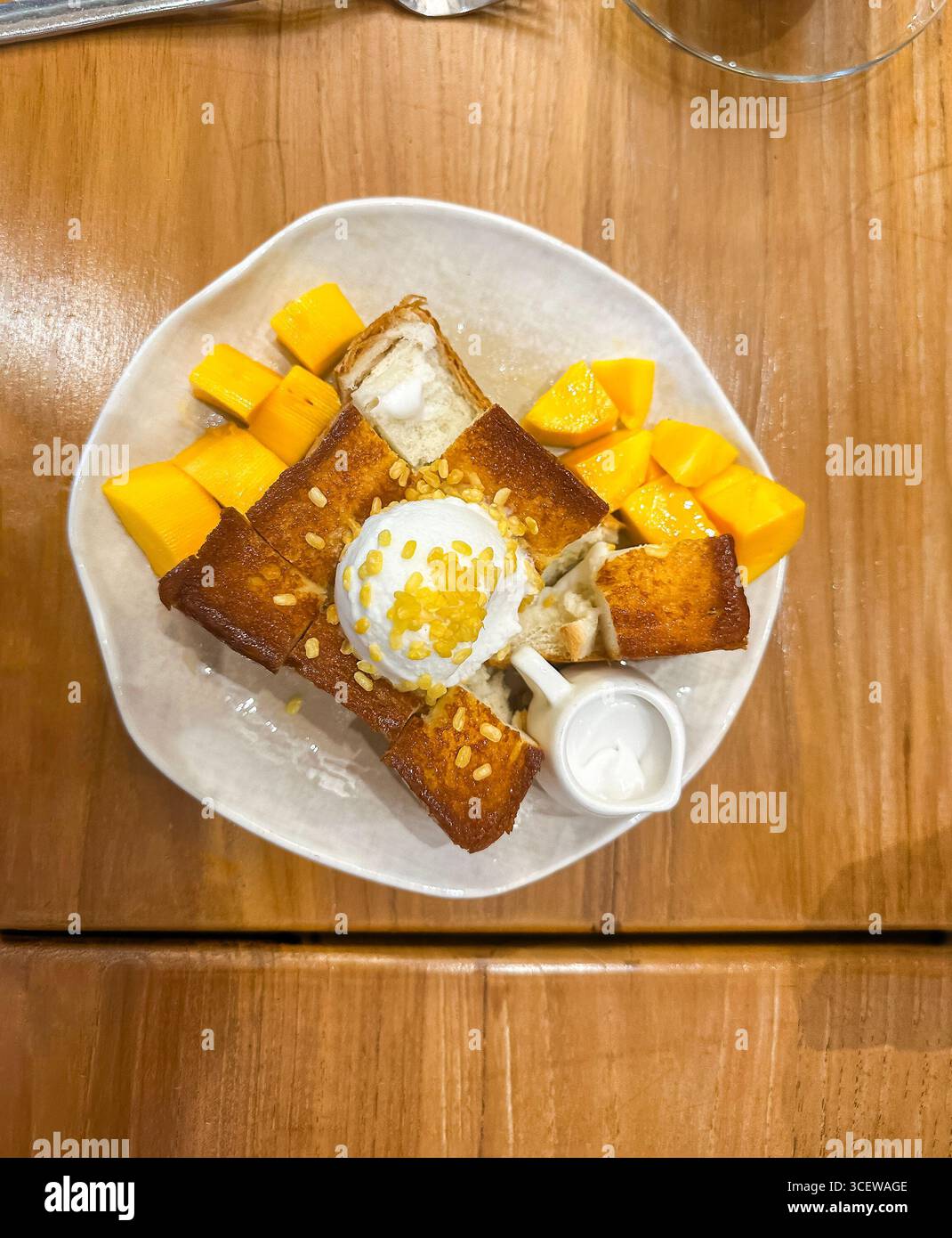 Vue aérienne de pain grillé au miel servi avec de la crème glacée et des tranches de mangue fraîche sur une table en bois. Malacca malaisie - Image de stock capturée avec un smartphone